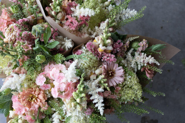 A close up of market bouquets with blooms in shades of peach, pink, and white.